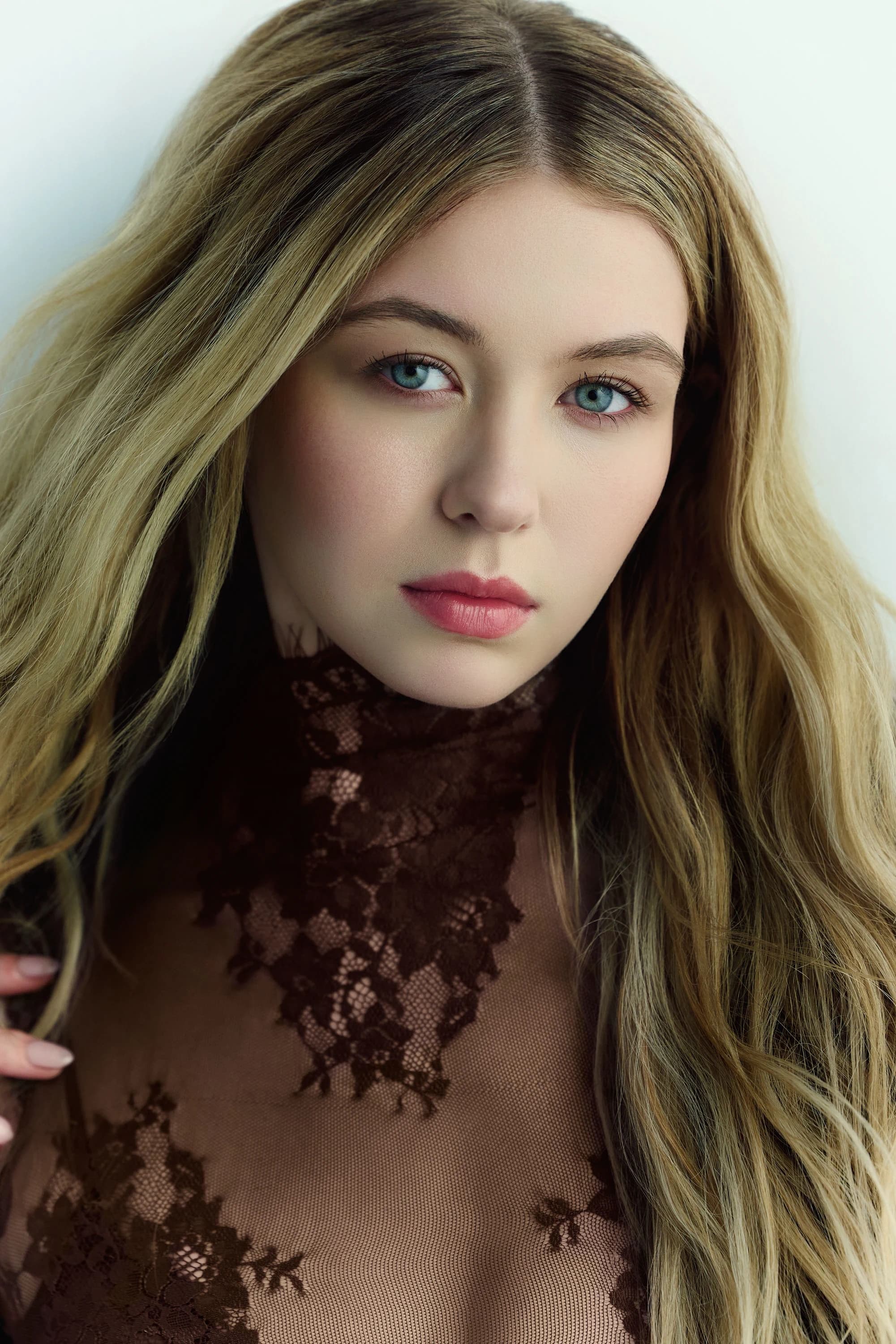 Close portrait of Sage Burress in a dark lace top, looking toward the camera.