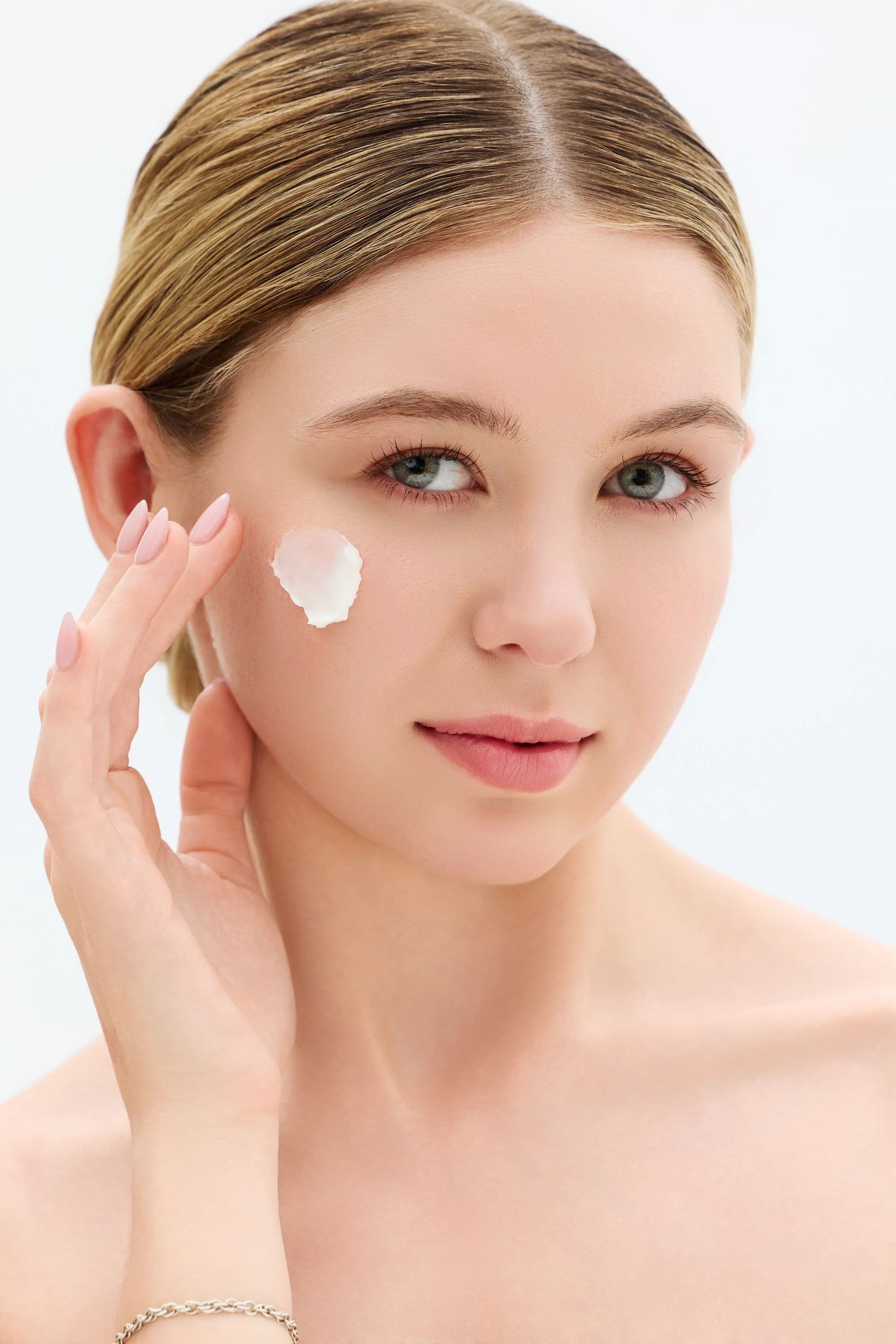 Beauty portrait of Sage Burress applying skincare against a white background.