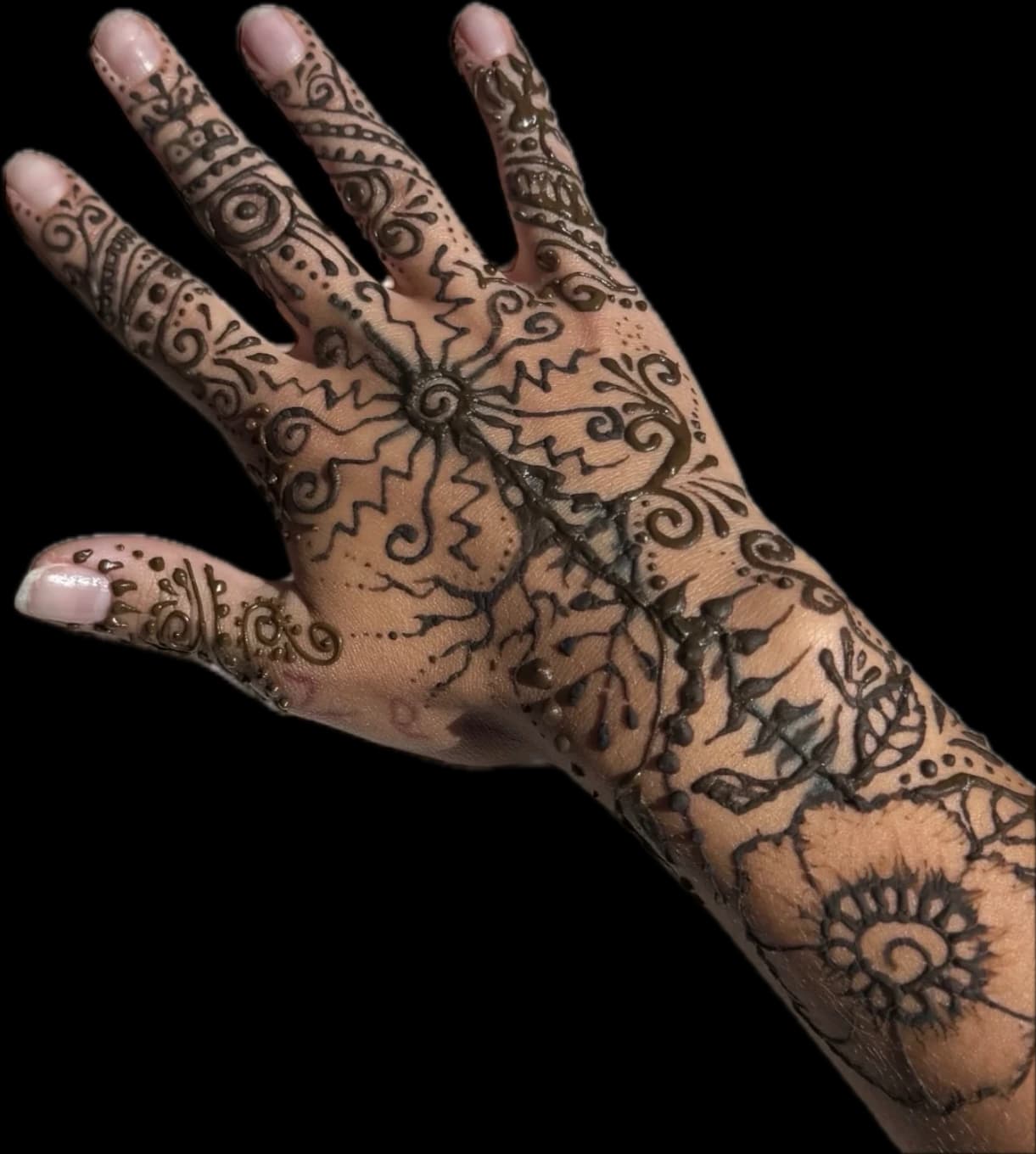 Intricate floral and geometric henna design across a hand and forearm.