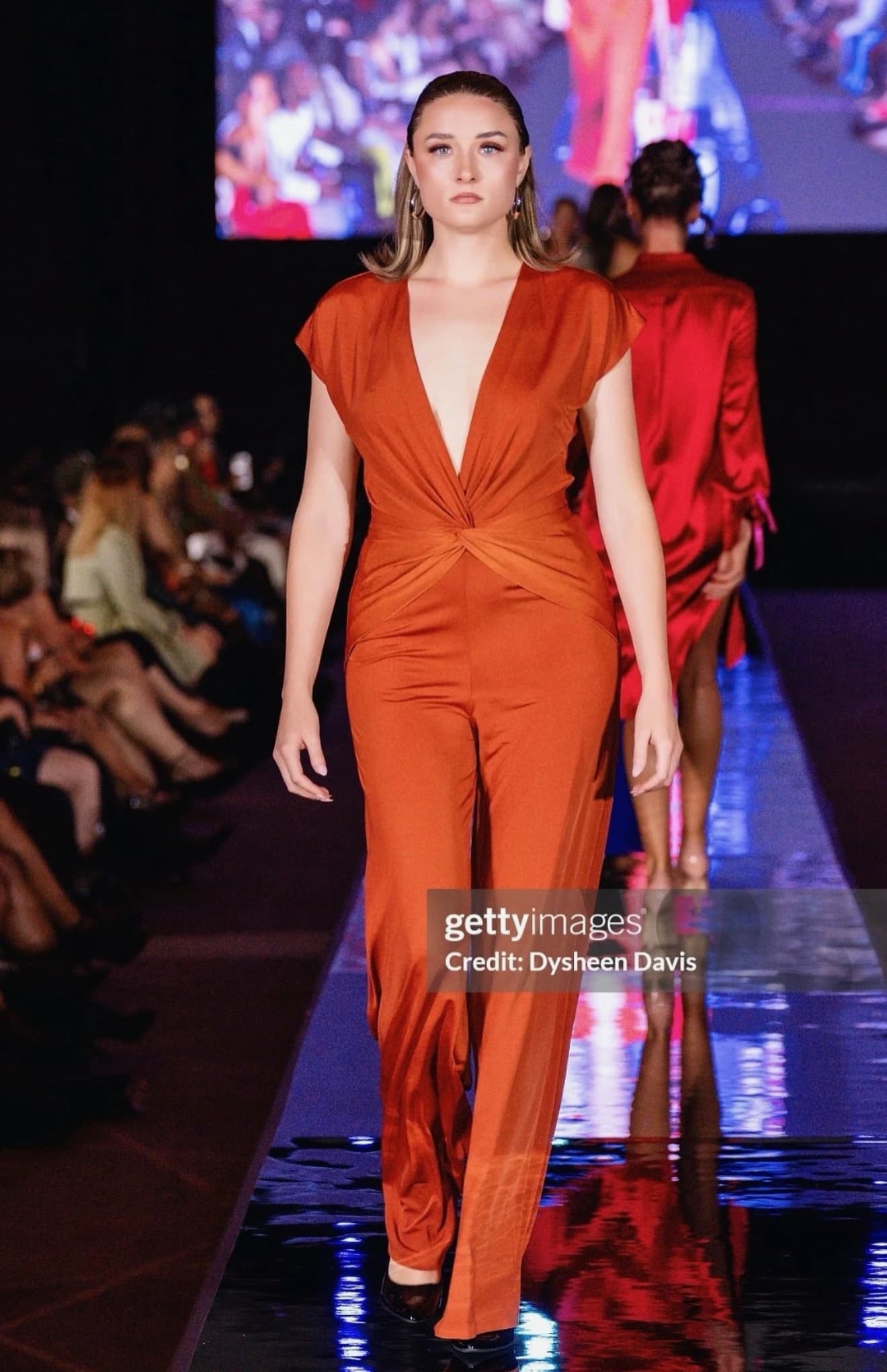 Runway model wearing polished makeup with a burnt-orange look.