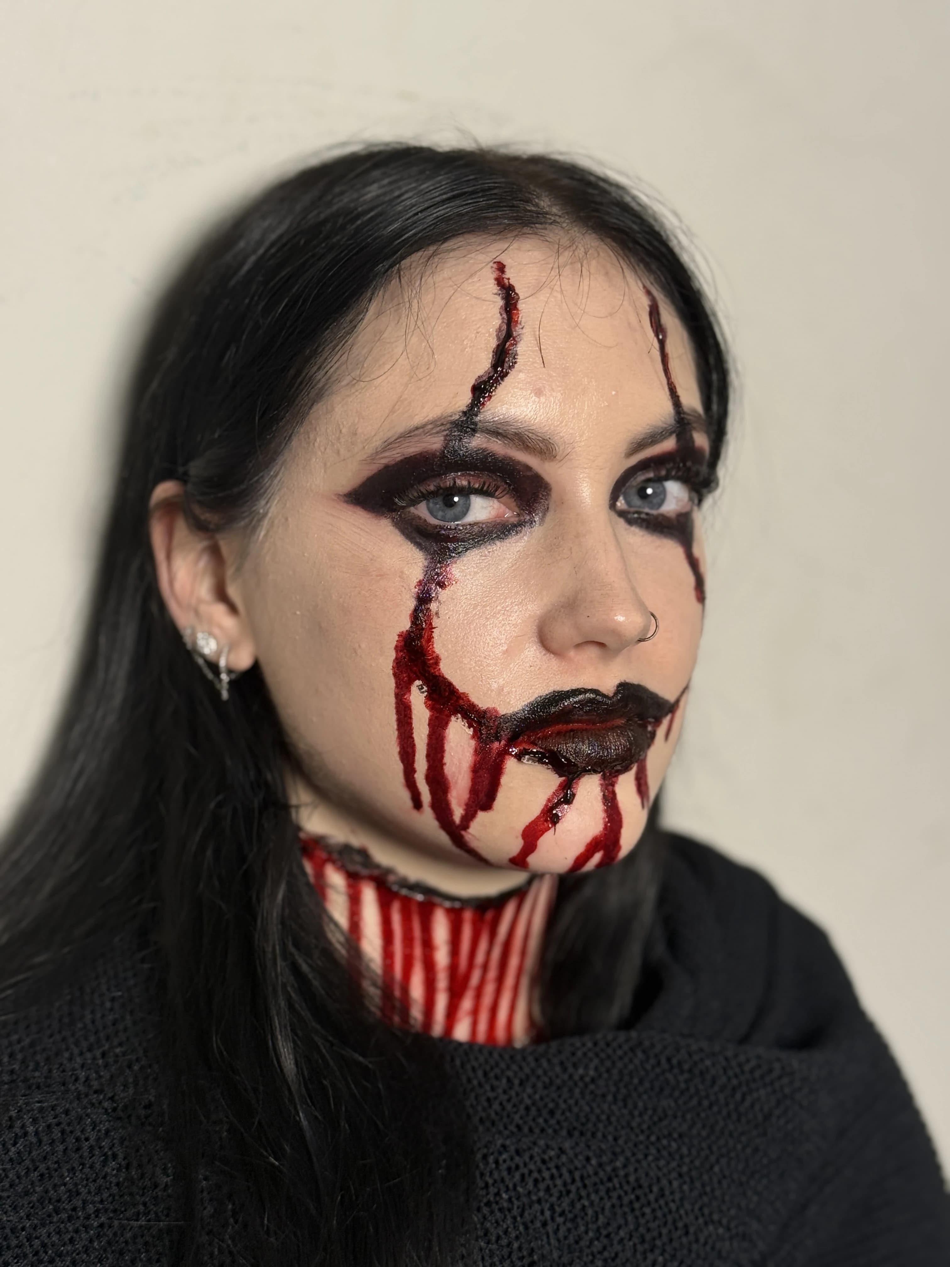 Creative theatrical makeup with deep black and red details.