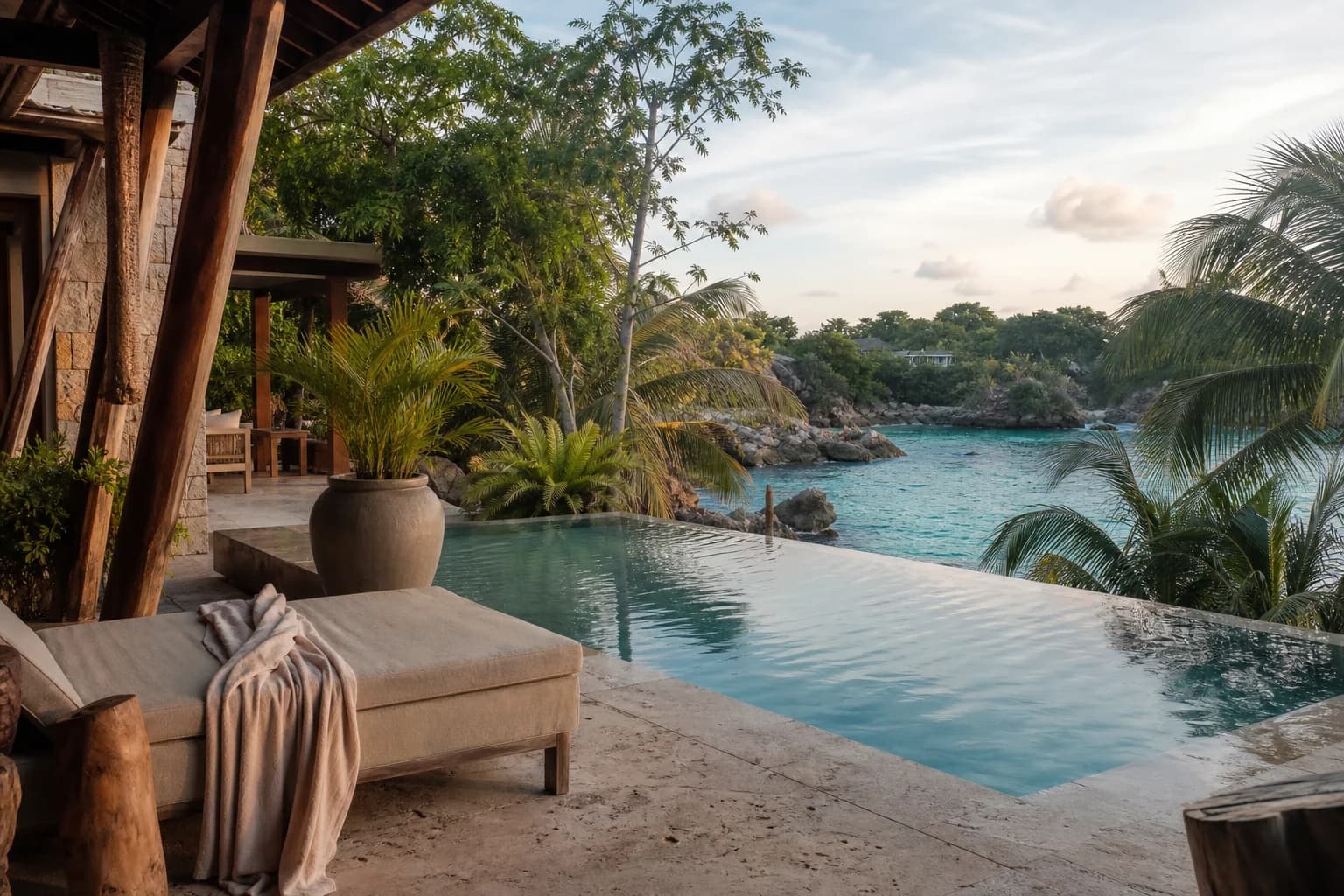 Tropical resort terrace overlooking an infinity pool and a coastal cove.